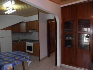 a kitchen with wooden cabinets and a table in a room at Novas Foxos (Ático) in A Lanzada