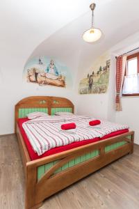 a bedroom with a wooden bed with red pillows on it at Apartments Petacova Hiša in Kranjska Gora