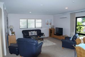 sala de estar con sillas azules y TV en Ocean Breeze Resort Pauanui en Pauanui