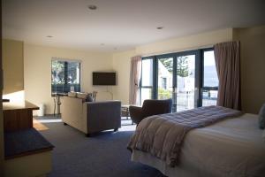 アカロアにあるAkaroa Criterion Motelのベッドと椅子付きのホテルルーム