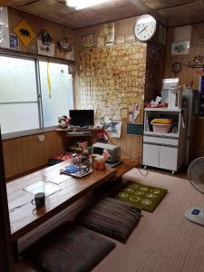 uma cozinha com uma mesa, um frigorífico e um relógio em Tomarigi em Yakushima
