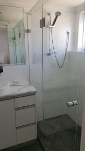 y baño con ducha acristalada y lavamanos. en Banyandah Towers, en Maroochydore