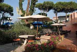 patio ze stołami, krzesłami i parasolami w obiekcie Versilia Palace Hotel w mieście Marina di Pietrasanta