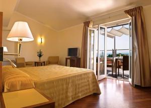 ein Hotelzimmer mit einem Bett und einer Glasschiebetür in der Unterkunft Versilia Palace Hotel in Marina di Pietrasanta