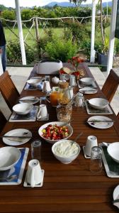a wooden table topped with plates and bowls of food at Jacaranda Lodge in Coromandel Town +11 photos