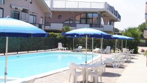a pool with chairs and umbrellas next to a building at Polena Residence Hotel in Marina di Montenero