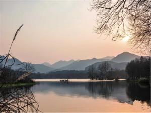 a view of a lake with mountains in the background at Yurong West Lake Cottage Resort Hotel Hangzhou in Hangzhou