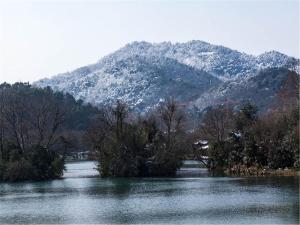 a river with trees and a mountain in the background at Yurong West Lake Cottage Resort Hotel Hangzhou in Hangzhou
