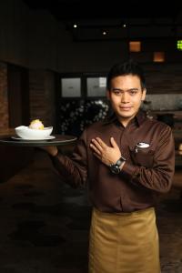 un homme tenant une assiette avec un dessert dans l'établissement Midtown Hotel Samarinda, à Samarinda