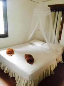a white bed with two pillows on top of it at Tropical Garden Bungalow in Phi Phi Don