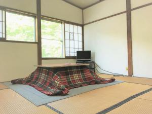 a room with a table with a blanket on the floor at Ichinokurasou in Hakuba