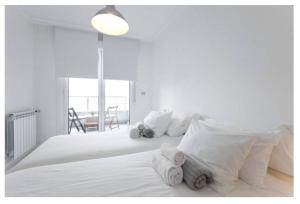 um quarto branco com uma grande cama branca com almofadas brancas em White Cozy Flat in Donostia em San Sebastián
