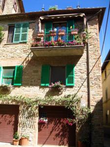 um edifício de tijolos com janelas verdes e caixas de flores em Trasimeno Panicale - Appartamento borgo storico em Panicale