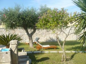 オートラントにあるLa casa del contadinoのベンチと木々と石壁の庭園