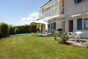 a house with a lawn with chairs and an umbrella at Alpes et Lac in La Neuveville