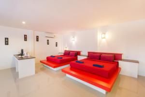 two beds in a white room with red pillows at Da Kanda Villa Beach Resort in Thongsala