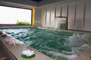 a pool with a waterfall in a room with flowers at Tus'Hotel in Castel di Tusa
