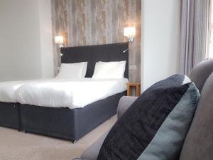 
a hotel room with a bed, chair, and nightstand at Ocean Beach Hotel & Spa - OCEANA COLLECTION in Bournemouth
