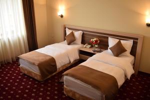 2 camas en una habitación de hotel con flores en una mesa en Artsakh Hotel en Ereván