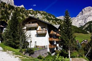 a building in the mountains with trees in front of it at Pensione Sellablick in Colfosco