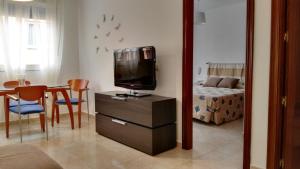 a living room with a tv on a dresser and a bedroom at Piso Geneto con garaje in Las Lagunas