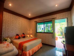 a bedroom with a bed and a window and a television at Samroiyod Holiday Resort in Sam Roi Yot