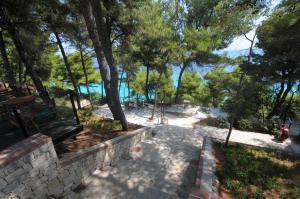a walkway with trees and a view of the water at Nostos Hotel in Afitos