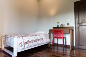 Schlafzimmer mit einem Bett, einem Schreibtisch und einem roten Stuhl in der Unterkunft Modern Thai Home in Ban Mae Mae