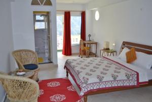 a bedroom with a bed and chairs and a window at Seventh Heaven Inn Rishikesh in Rishīkesh +33 photos