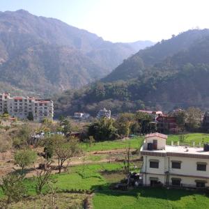 a house in a field with mountains in the background at Seventh Heaven Inn Rishikesh in Rishīkesh