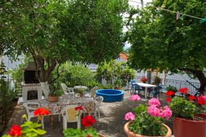 a patio with tables and chairs and flowers at Nikos Rooms in Votsi