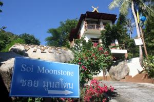a sign in front of a building with flowers at Moonstone Studio in Haad Rin