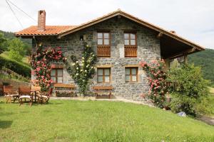 una casa de piedra con una mesa y sillas delante de ella en Casa Carielda en Pembes