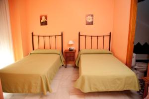 two beds in a room with two lamps on each side at Hostal Niza in San Juan del Puerto