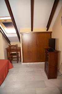 1 dormitorio con 1 cama y TV en un armario de madera en Hostal Niza en San Juan del Puerto