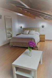 Un dormitorio con una cama y una mesa con un jarrón de flores en El Rincon del Cuera, en Parres de Llanes