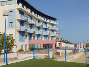 a large apartment building with blue balconies and a playground at Tus'Hotel in Castel di Tusa
