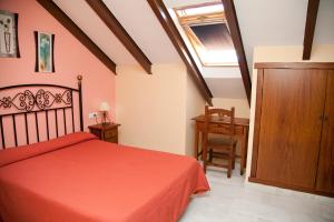 a bedroom with a red bed and a wooden cabinet at Hostal Niza in San Juan del Puerto
