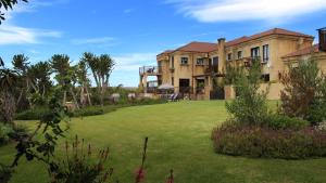 une grande maison avec une pelouse devant elle dans l'établissement Dio Dell Amore Guest House, à Jeffreys Bay