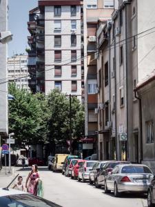 dos chicas caminando por una calle de la ciudad con coches en Apartment Niš Center, en Niš