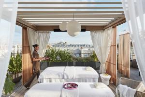 a man standing on a balcony with two beds at Mandarin Oriental, Paris in Paris