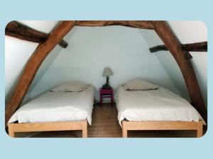 two beds in a attic with a lamp on a table at La Ferme du Parc in Pendé