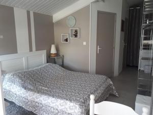 a bedroom with a bed with a gray comforter at Le Soleil Couchant in Angresse