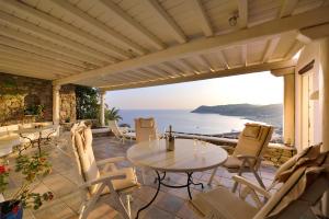 een patio met een tafel en stoelen en de oceaan bij Mykonian Dianthus in Elia Beach