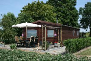 een kleine hut met een tafel en stoelen en een parasol bij Bie Oans Oefje in Lewedorp