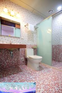 a bathroom with a toilet and a tiled wall at Zhen Ai B&B in Wujie