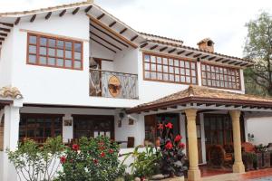 a white house with a balcony and red flowers at Hotel Boutique Villa Roma in Villa de Leyva