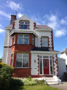 a red and white house with a red door at Witchingham B&B in Holyhead