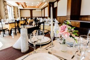 - une table avec des assiettes, des verres et des fleurs dans l'établissement Hotel Alisa, à Pavel Banya