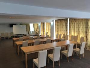 une salle de conférence avec des tables, des chaises et un écran dans l'établissement Hotel Story, à Târgu Jiu